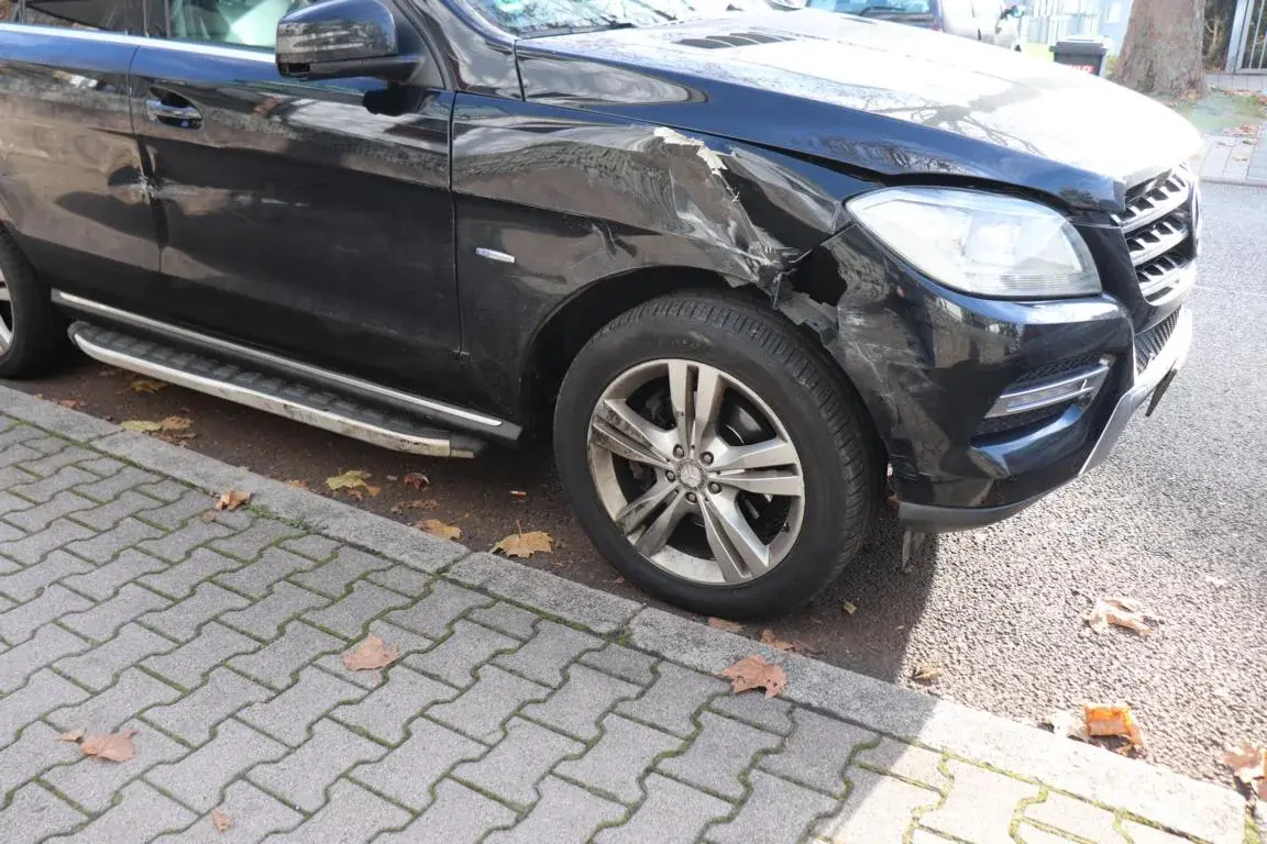 Front- und Kotflügelschaden an einem dunklen SUV bei der Schadenaufnahme